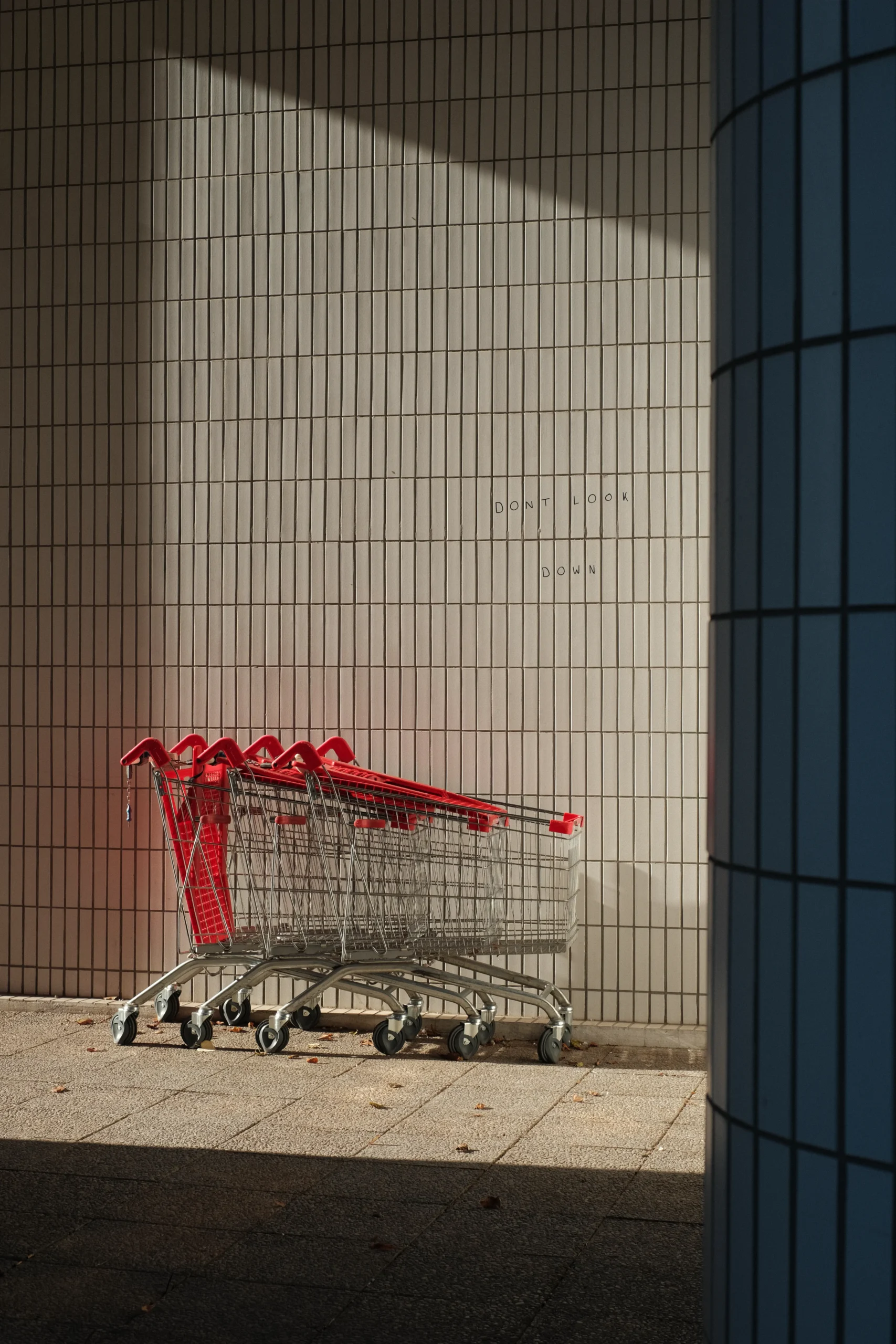 chariots de supermarché empilés contre un mur carrelé à Mériadeck, Bordeaux, photographie de rue Fujifilm