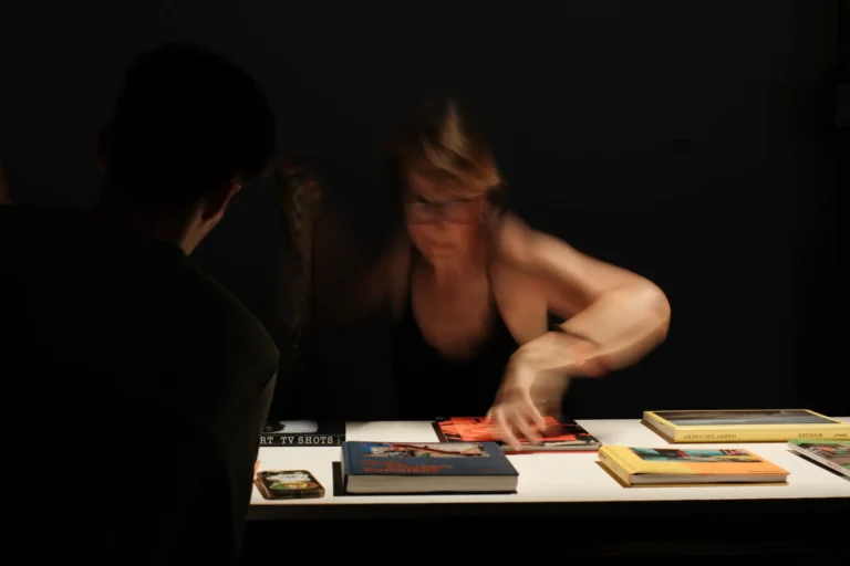 personne feuilletant des livres photo sur une table lors d'une expo aux Rencontres d'Arles, effet de flou de mouvement Fujifilm